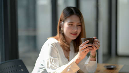 Cropped shot of a woman take a break and holding coffee cup while sitting in simple working place