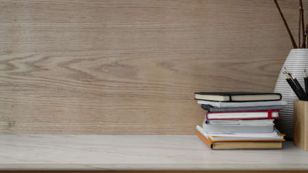 Close up view of simple workplace with copy space, books, stationery and ceramic vase on marble desk with modern rustic wallの写真素材