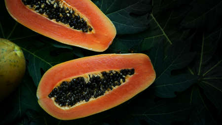 Top view of Papaya, tropical fruit, slice of sweet papaya on papaya leaves background の写真素材