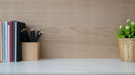 Close up view of simple workplace with copy space, book, stationery and tree pot on marble desk with...