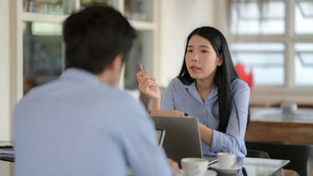 Cropped shot of two businesspeople siting opposite each other while consulting on their work with  computer laptopの写真素材