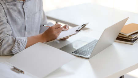 Cropped shot of young male entrepreneurs working with laptop and document file on white wooden desk