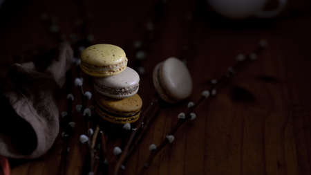 Close up view of sweet colourful Macarons on rustic table with pussy willow and brown napkin...