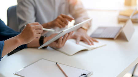 Cropped shot of two businesspeople consulting on their work with digital tablet, document file and...
