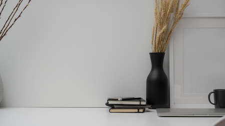 Close up view of minimal workspace with laptop, coffee cup, decorations and copy space on white desk with white wall backgroundの写真素材