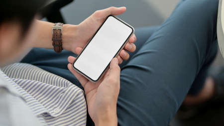 Close up view of male entrepreneur holding smartphone while resting at workplace