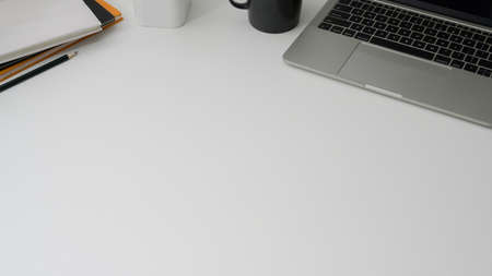 Cropped shot of minimal workspace with laptop, office supplies and copy space on white table backgroundの写真素材