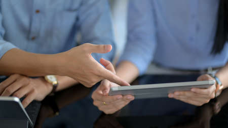 Close up view of businesspeople consulting on their project with digital tablet on black table in co-working spaceの写真素材