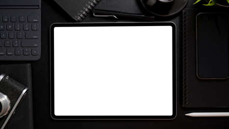 Overhead shot of dark modern workspace with mock- up digital tablet, stylus, camera and other office supplies on black deskの写真素材