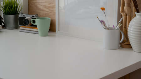 Cropped shot of simple designer workspace with mock-up frame, camera, painting brush, copy space and...