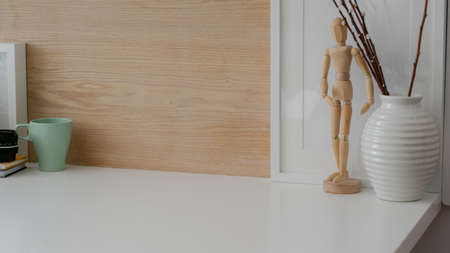 Cropped shot of simple workspace with mock-up frame, copy space and decorations on white table with...
