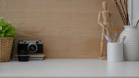 Close up view of simple designer workspace with camera, painting brush, copy space and decorations on white table の写真素材
