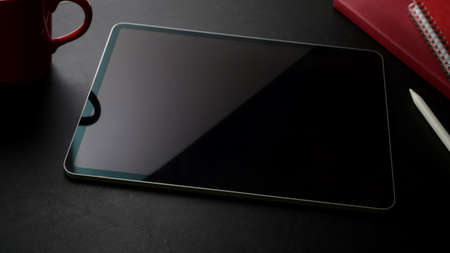 Cropped shot of stylish workspace with digital tablet and office supplies on black table 