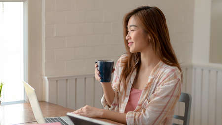 Cropped shot of happy young college girl take a break and drinking coffee in modern living room