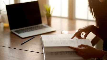 Cropped shot of young college girl preparing for her final exam on wooden table in modern living...