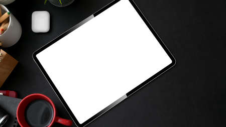 Top view of stylish workplace with mock-up tablet, stylus and red coffee cup on black table  