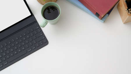 Overhead shot of trendy workplace with mock-up tablet, coffee cup, stationery and copy space on...