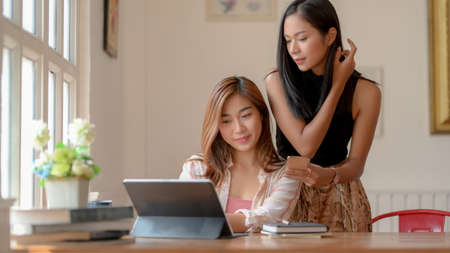Cropped shot of two young college girls consulting on their assignment with digital tablet and...