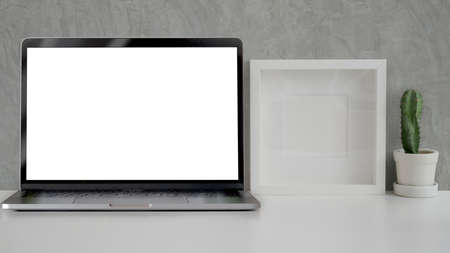 Close up view of minimal workplace with mock-up, laptop, frame and cactus pot  on white table with...