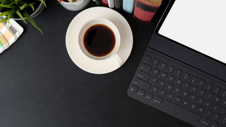 Top view of trendy workspace with mock-up tablet, coffee cup, books and copy space on black table  の写真素材