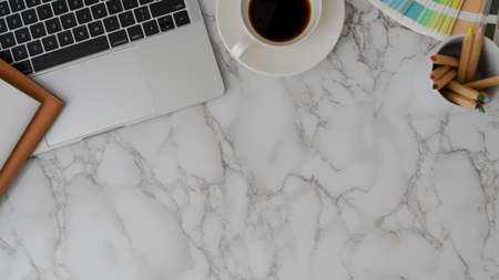Top view of modern designer workspace with laptop, coffee cup, painting tools and copy space on...