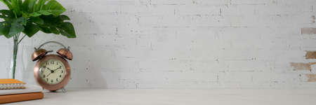 Cropped shot of minimal copy space with books, clock and decorations on white table with white brick...