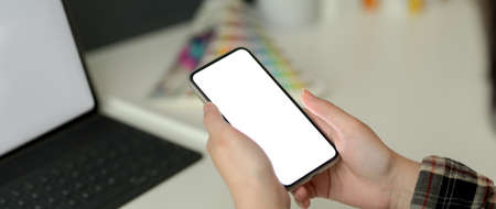 Cropped shot of female designer using mock-up smartphone while working with tablet and designer...