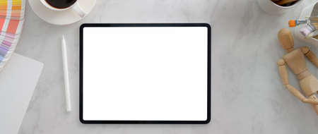 Cropped shot of minimal designer workspace with mock-up tablet, designer supplies and coffee cup on...
