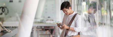 Cropped shot of young male photographer checking picture on digital camera while standing in glass wall officeの写真素材