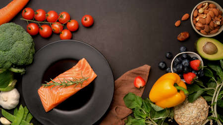 Top view of  healthy food, organic raw with salmon, fruits, vegetable, seeds and copy space on dark...