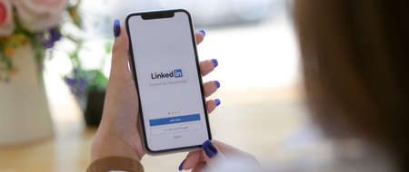 Foto de CHIANG MAI, THAILAND - MARCH 13, 2020 : female holding iPhone with Linkedin screen. Linkedin is mobile application for searching career opportunities - Imagen libre de derechos