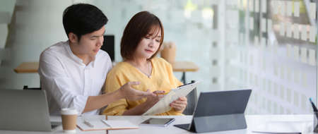 Cropped shot of two businesspeople sitting in glass glass wall office room and consulting on their projectの写真素材