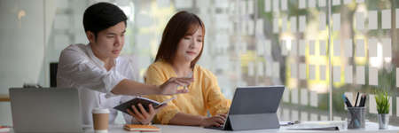 Cropped shot of two businesspeople sitting in glass partition and consulting on their project
