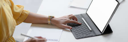 Cropped shot of female entrepreneur focusing on her work with mock-up tablet  on white table