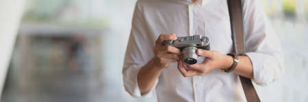 Close up view of young male photographer checking his photo on digital camera while standing in glass wall co-working space  の写真素材