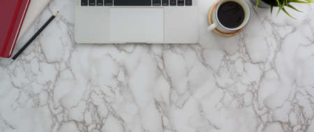 Top view of trendy workspace with laptop, stationery, coffee cup and copy space on marble desk
