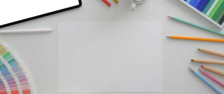 Overhead shot of designer workplace with mock-up tablet, sketch paper and designer supplies on white desk  の写真素材
