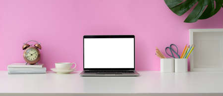 Close up view of feminine workspace with blank screen laptop, supplies and decorations on white...