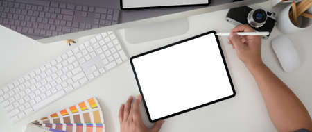Overhead shot of male graphic designer working on mock-up tablet with camera computer device and...
