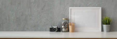 Cropped shot of trendy workspace with camera, mock-up frame, decorations and copy space on marble...