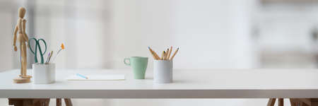 Cropped shot of designer workspace with designer supplies, coffee cup, books and copy space on white...