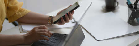 Cropped shot of female entrepreneur concentrating on her work with digital tablet and smartphone on...