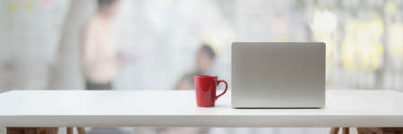 Cropped shot of portable workspace with laptop, coffee cup and copy space on white table with...