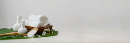 Cropped shot of Spa accessories with towel, aroma oil and herbal compressing balls on banana leaf and copy space on marble tableの写真素材