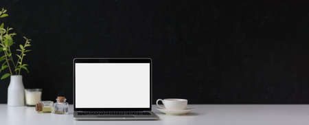 Cropped shot of dark modern concept workspace with copy space, mock-up laptop, coffee cup and decorations on marble desk  の写真素材