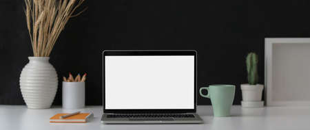 Close up view of dark modern workspace with mock-up laptop, supplies and decorations on marble desk 