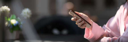 Side view of female freelancer using smartphone while sitting in dark modern coffee shop