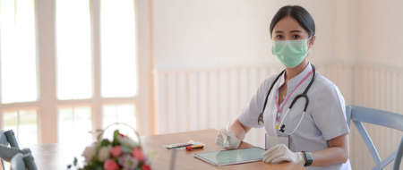 Cropped shot of female doctor reading patient chart on digital tablet while sitting in examination room の写真素材