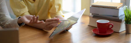 Cropped shot of two college girl working on their thesis with blank screen tablet and books on...