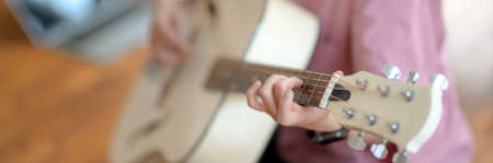 Close up view of young female music college student playing guitar while sitting in music practice...